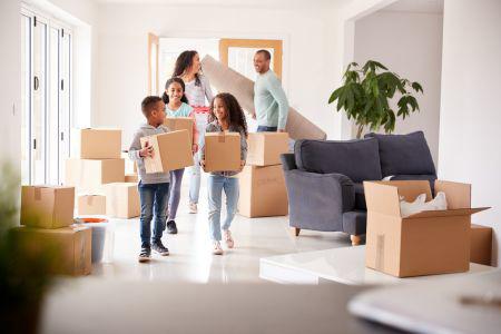 A family moving boxes into a living room