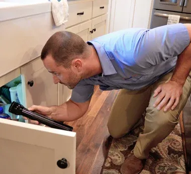 An employee inspecting a kitchen sink plumbing