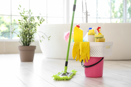 A mop and bucket filled with cleaning supplies sit on a bathroom floor, representing spring home cleaning and moisture prevention.